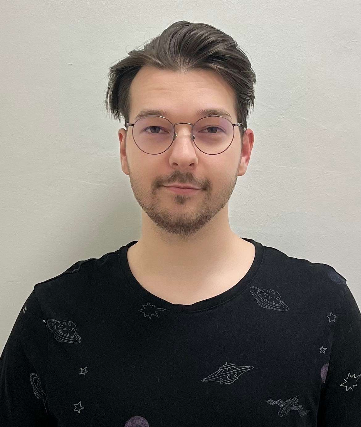 Király Zoltán smiling in a black shirt and round glasses